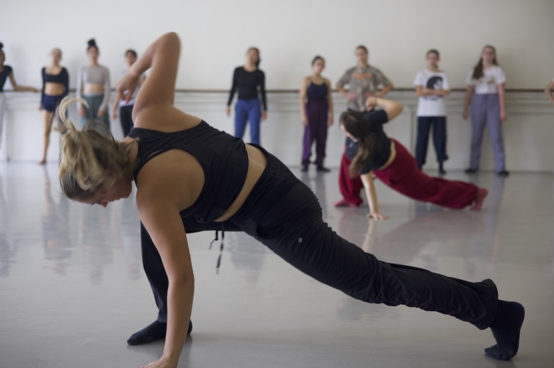 Dance students hold a lunge pose during a studio dance class